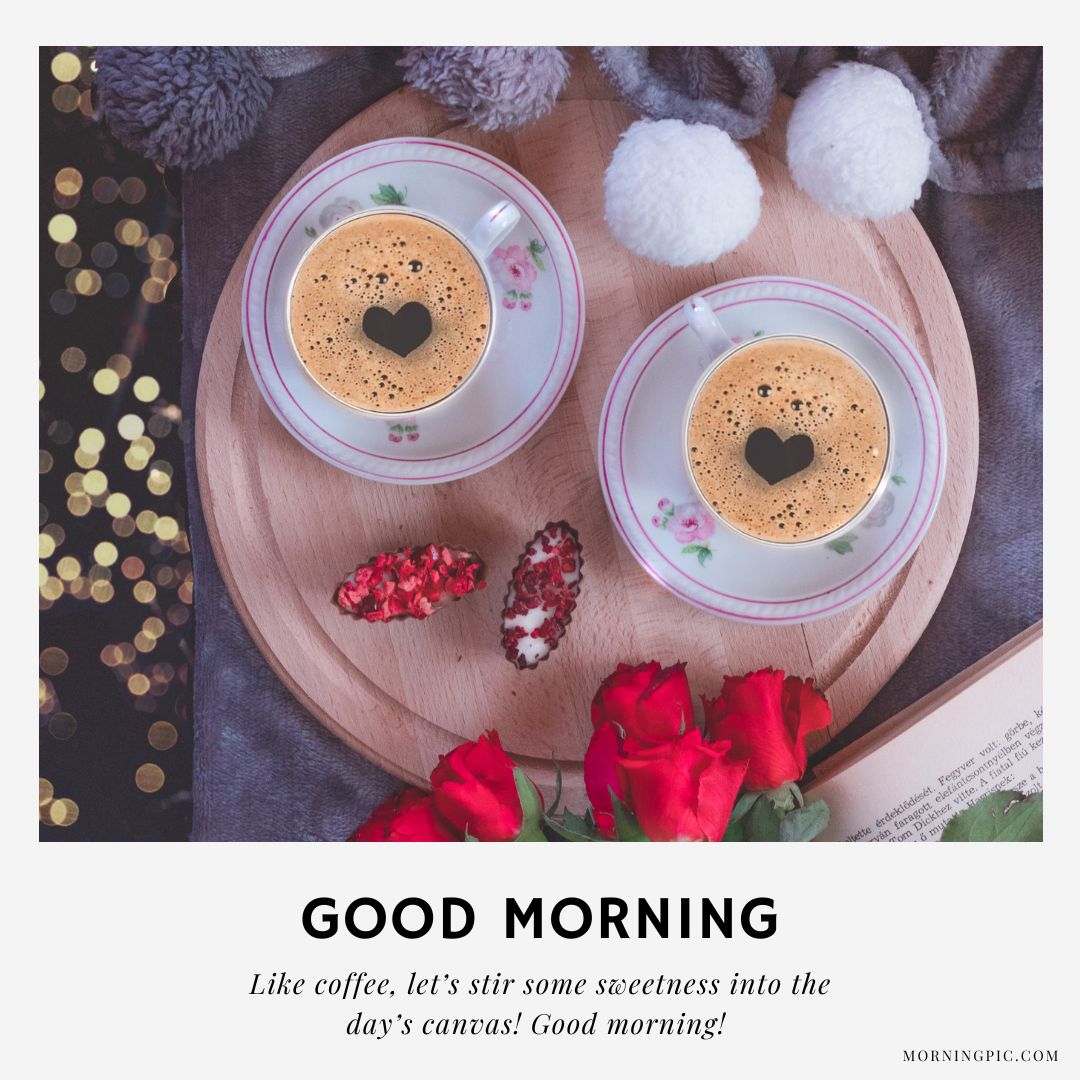 Two cups of coffee with heart-shaped foam on a wooden tray, surrounded by cozy items including knitwear pom-poms, red roses, and a book. Decorative lights add a warm ambiance. Text reads: "Good Morning" with an inspiring message to start the day—perfect examples of good morning coffee pictures.
