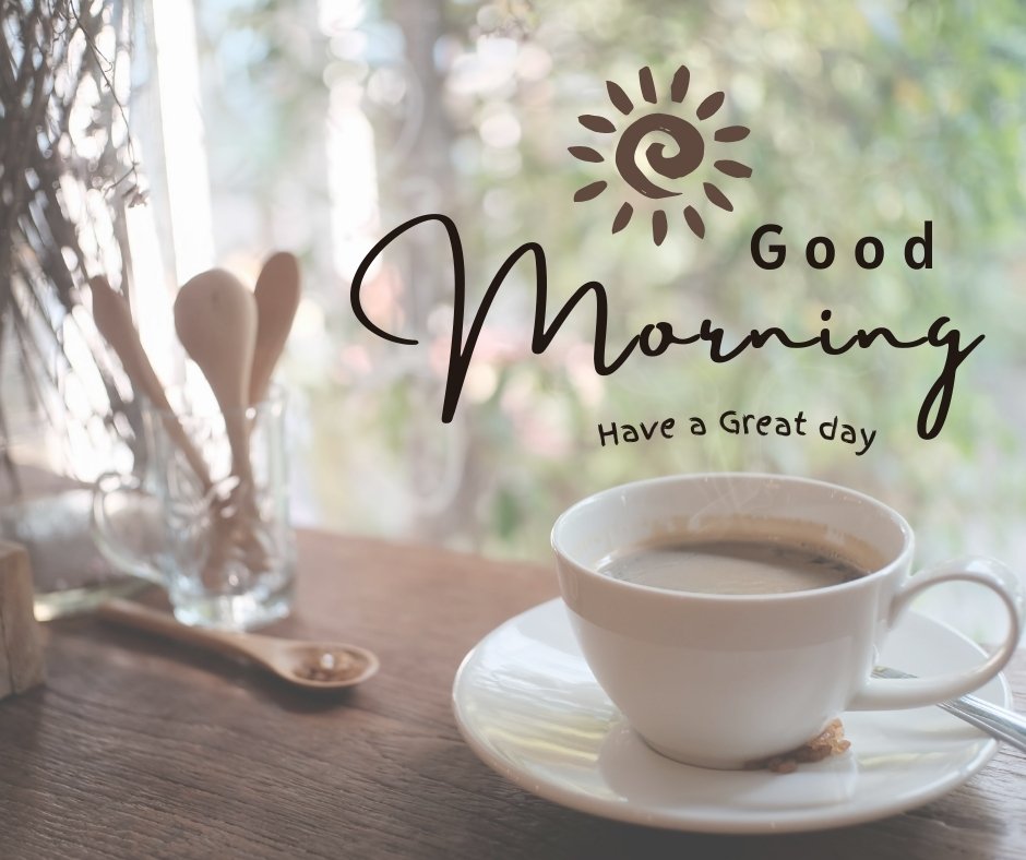 A white cup of coffee sits on a wooden table near a window, with a background of green foliage. The text overlay reads, "Good Morning. Have a great day" with a sun icon. This image is a serene example of good morning coffee images.